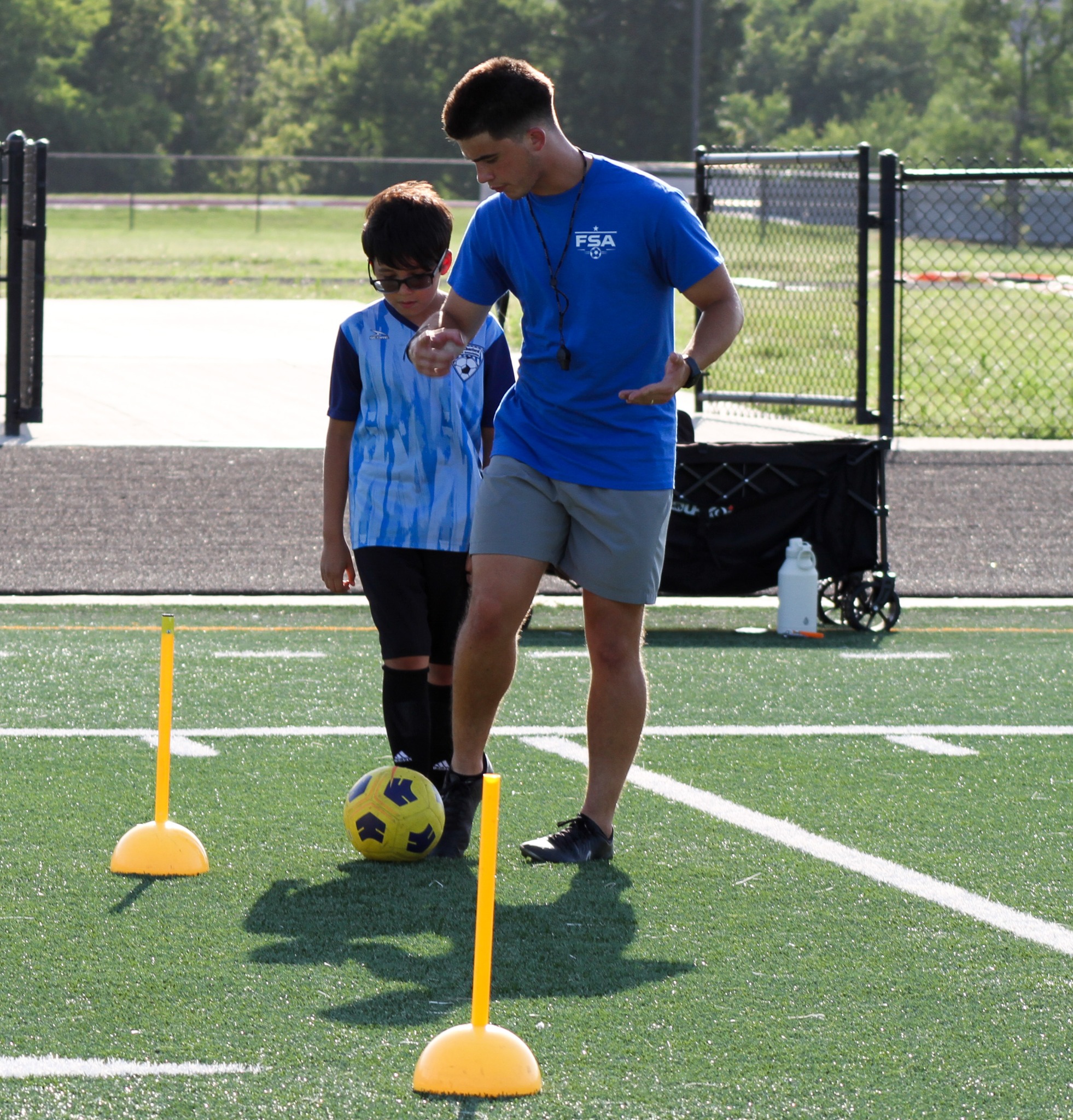 Coach Jose in a blue shirt giving direct feedback to a player